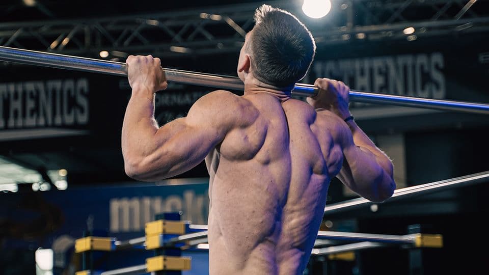 a man doing pull ups on a pull up bar at a calisthenics competition